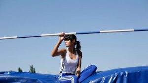 Female pole vaulter taking a break outdoors on a sunny day.